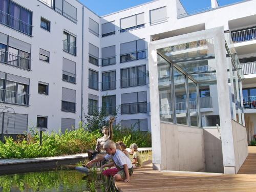 Children sitting at a pond in front of the staircase leading to the underground car park